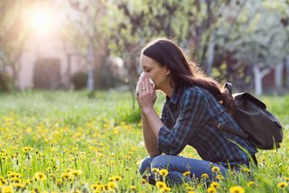 Pollenallergie Frau niest im Blumenfeld